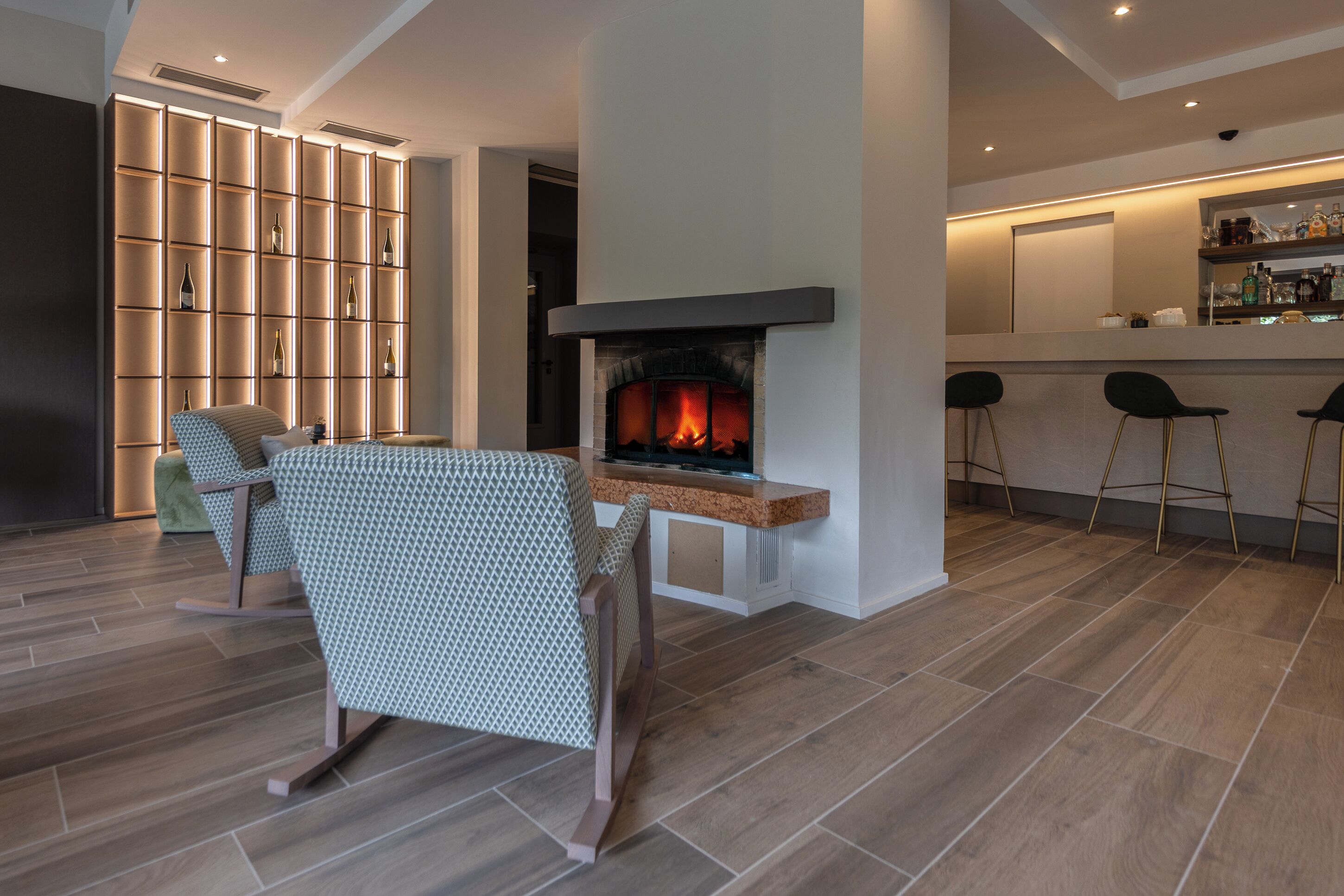 A modern living room with a fireplace, a seating area, and a bar with stools.
