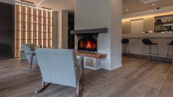 A modern living room with a fireplace, a seating area, and a bar with stools.