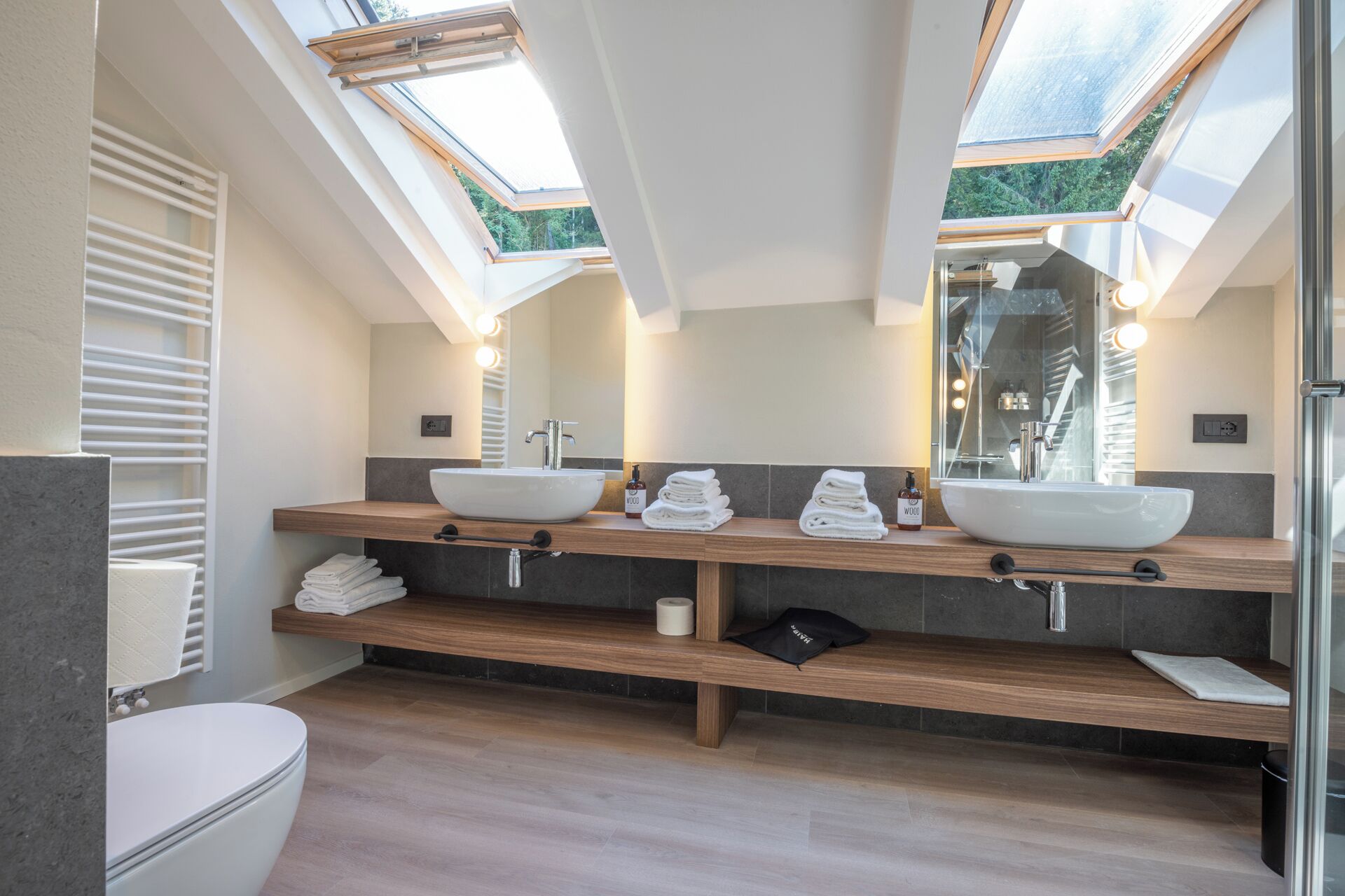 Une salle de bain moderne avec des fenêtres de toit, un double lavabo et des toilettes.