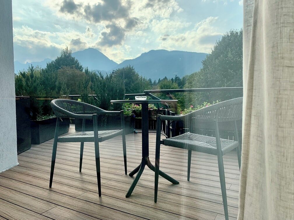 Un balcon avec une table et des chaises, donnant sur un paysage montagneux.