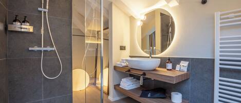 A modern bathroom with a glass-enclosed shower, a white sink, and a wooden vanity.