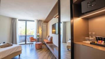 A modern hotel room with a bed, seating area, and a minibar.