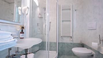 A bathroom with a glass-enclosed shower, a toilet, a sink with a mirror, and a towel rack.
