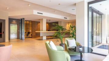 A spacious lobby with a reception desk, seating area, and a glass door leading outside.