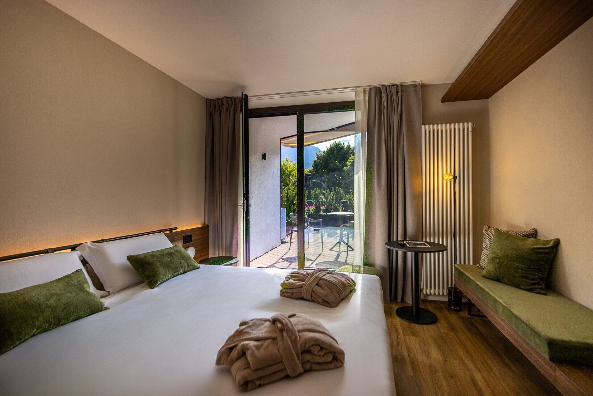 Habitación de hotel con cama, sofá, una mesita y vistas al exterior.