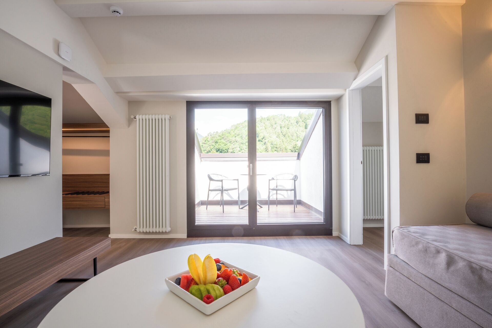 Una sala de estar moderna con una mesa de centro blanca, un sofá gris y un balcón con dos sillas.