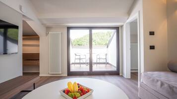 Una sala de estar moderna con una mesa de centro blanca, un sofá gris y un balcón con dos sillas.