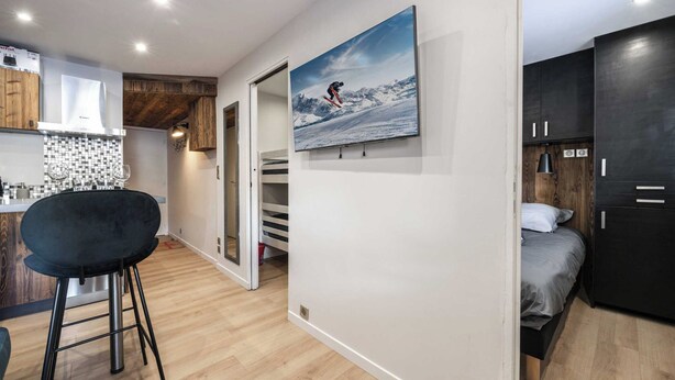 Une cuisine moderne avec une chaise noire, une table à manger et un grand tableau représentant un skieur accroché au mur.