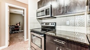 Uma cozinha moderna com armários escuros, micro-ondas, forno e fogão.