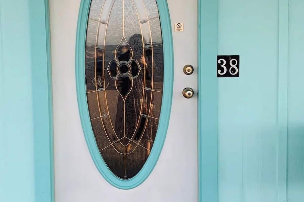 A teal-framed door with a glass panel, a number "38" sign, and a small yellow object above it.
