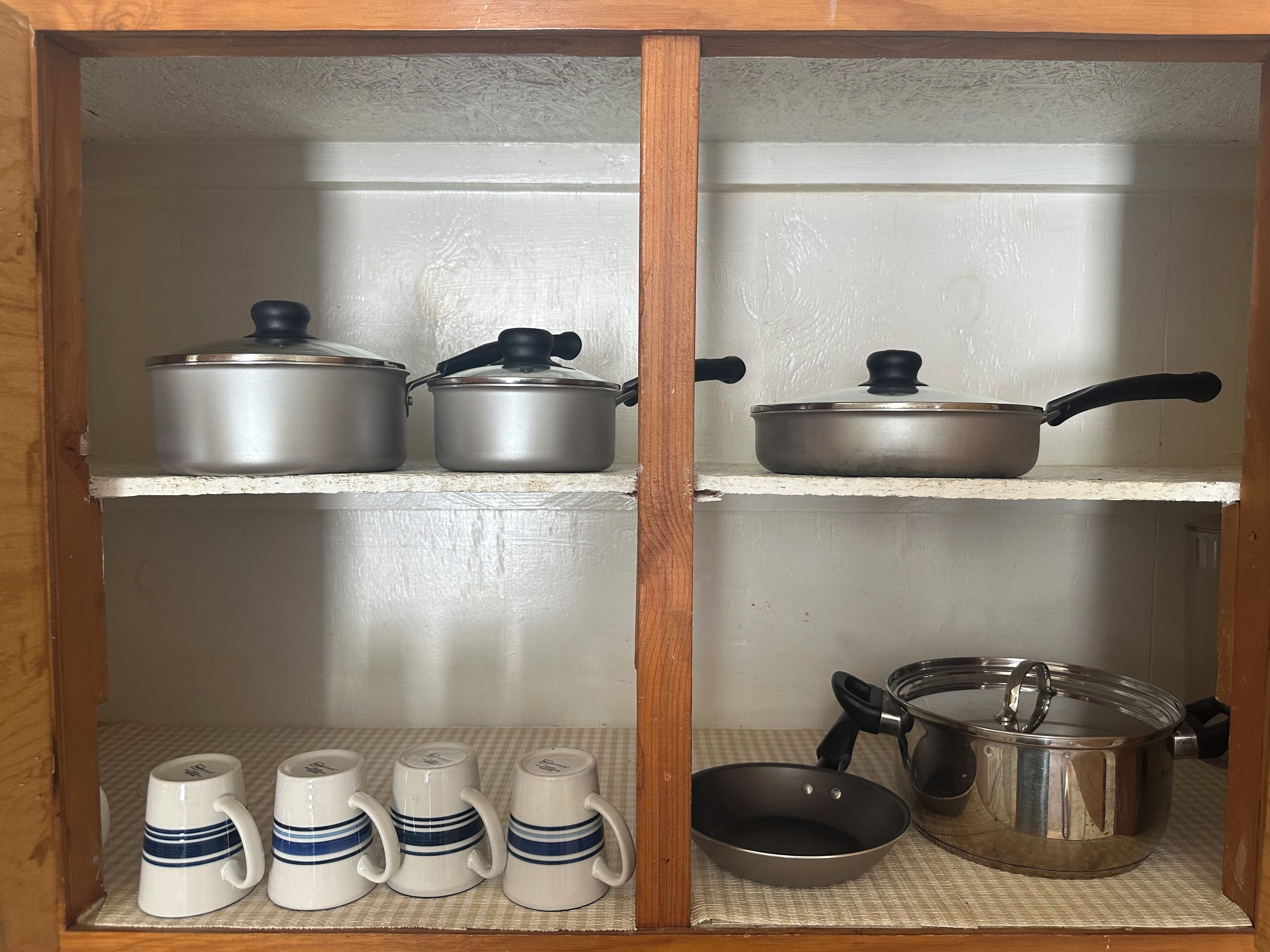 Um armário de madeira com prateleiras cheias de utensílios de cozinha.