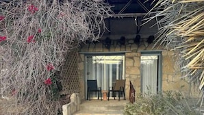 A stone pathway leading to a building with a covered patio area, stone steps, and a small garden with rocks and sparse vegetation. - Chisos Mining Co Motel (Terlingua)