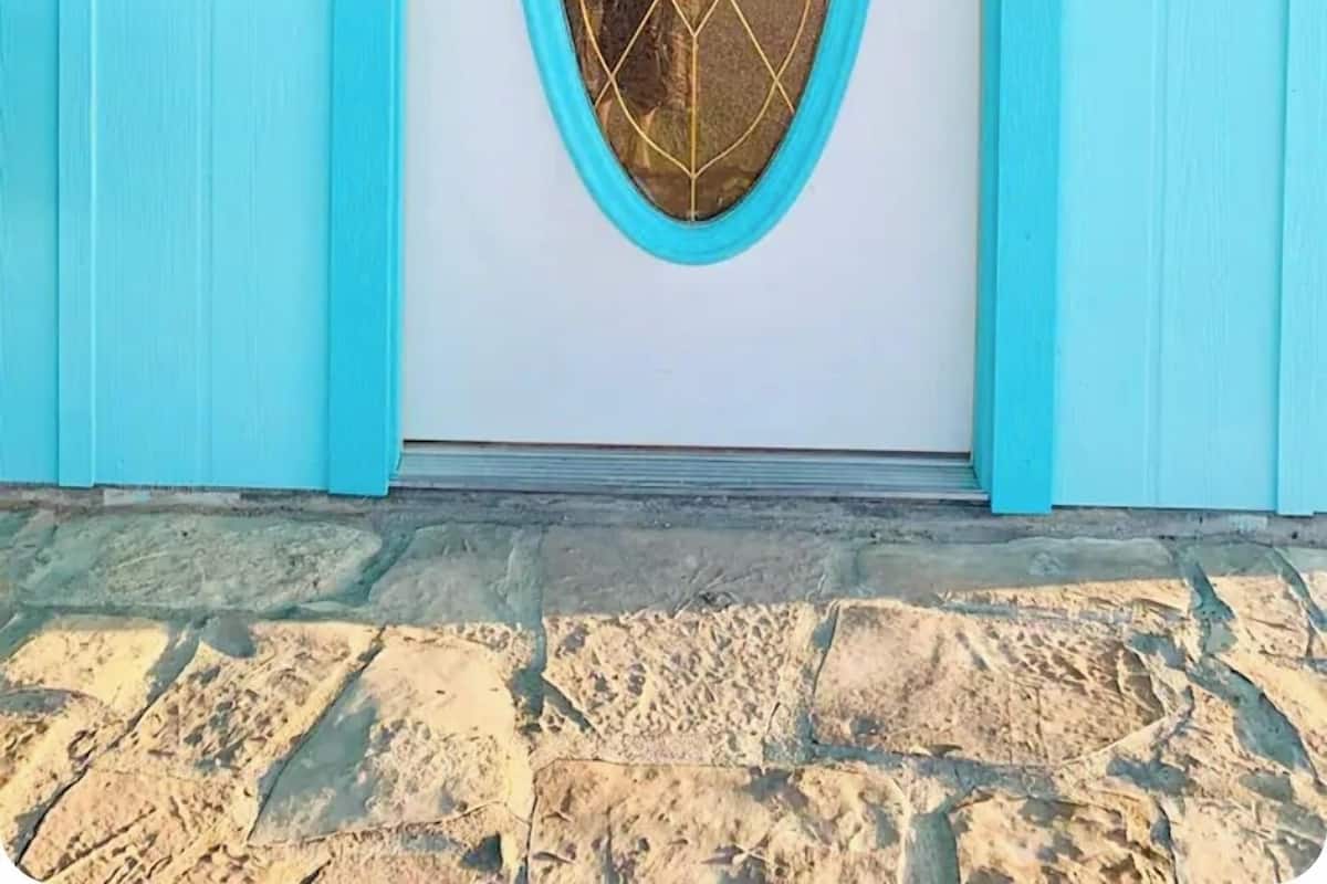A turquoise door with a glass panel, a number '37' sign, and a small light fixture above it.