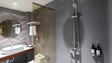 Un baño moderno con ducha de vidrio, un espejo redondo y un lavabo blanco.