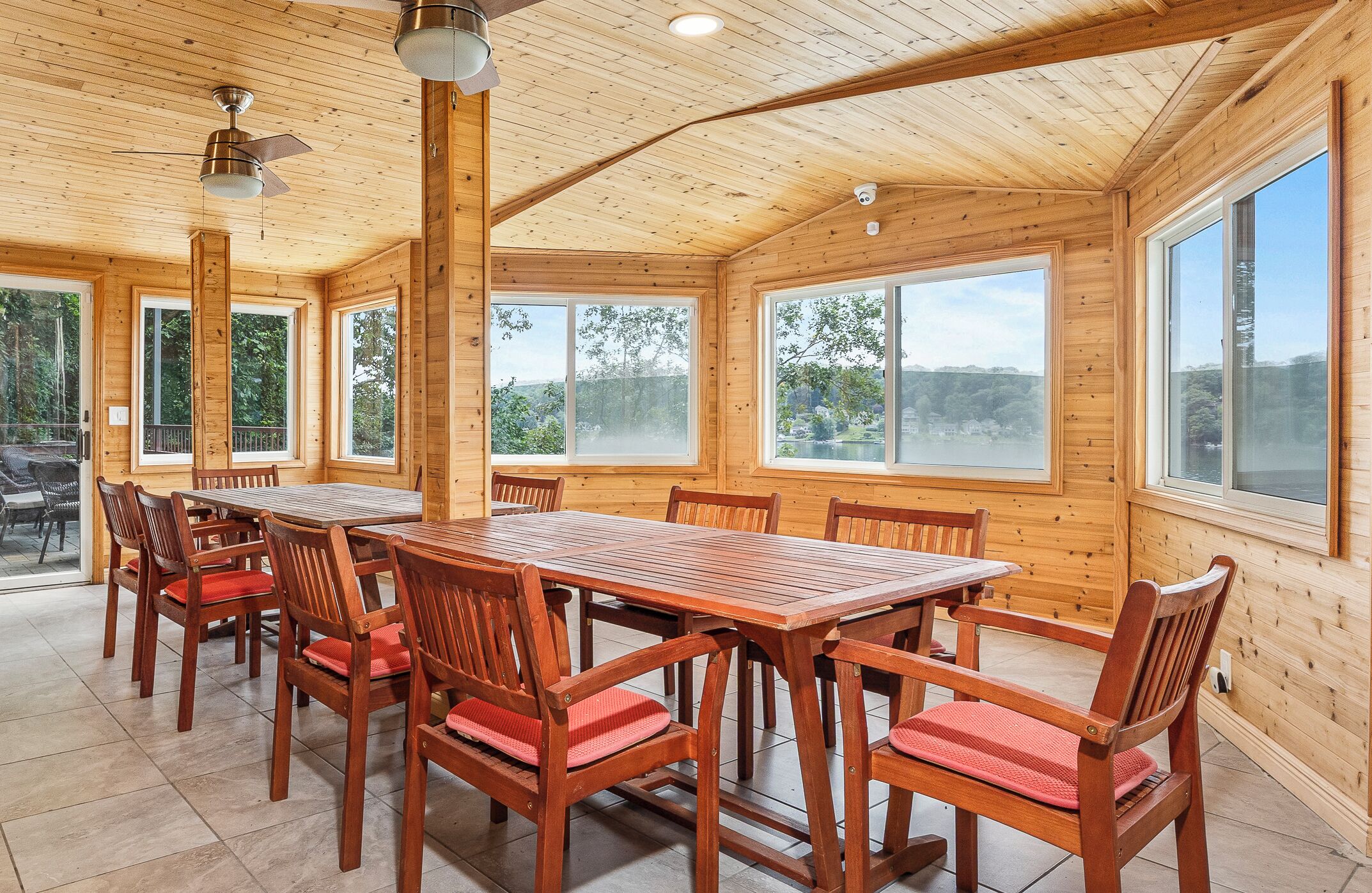 Interior de madera con una gran mesa de comedor y sillas, ventanas amplias que ofrecen vistas al exterior.