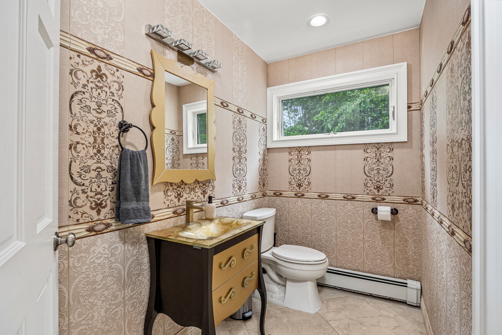 A bathroom with a vanity, toilet, and a window.