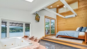 Een moderne badkamer met een ruime badkuip, een houten plafond en uitzicht op de natuur.