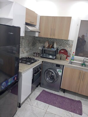 Una cocina compacta equipada con refrigerador, estufa, lavavajillas y lavadora.