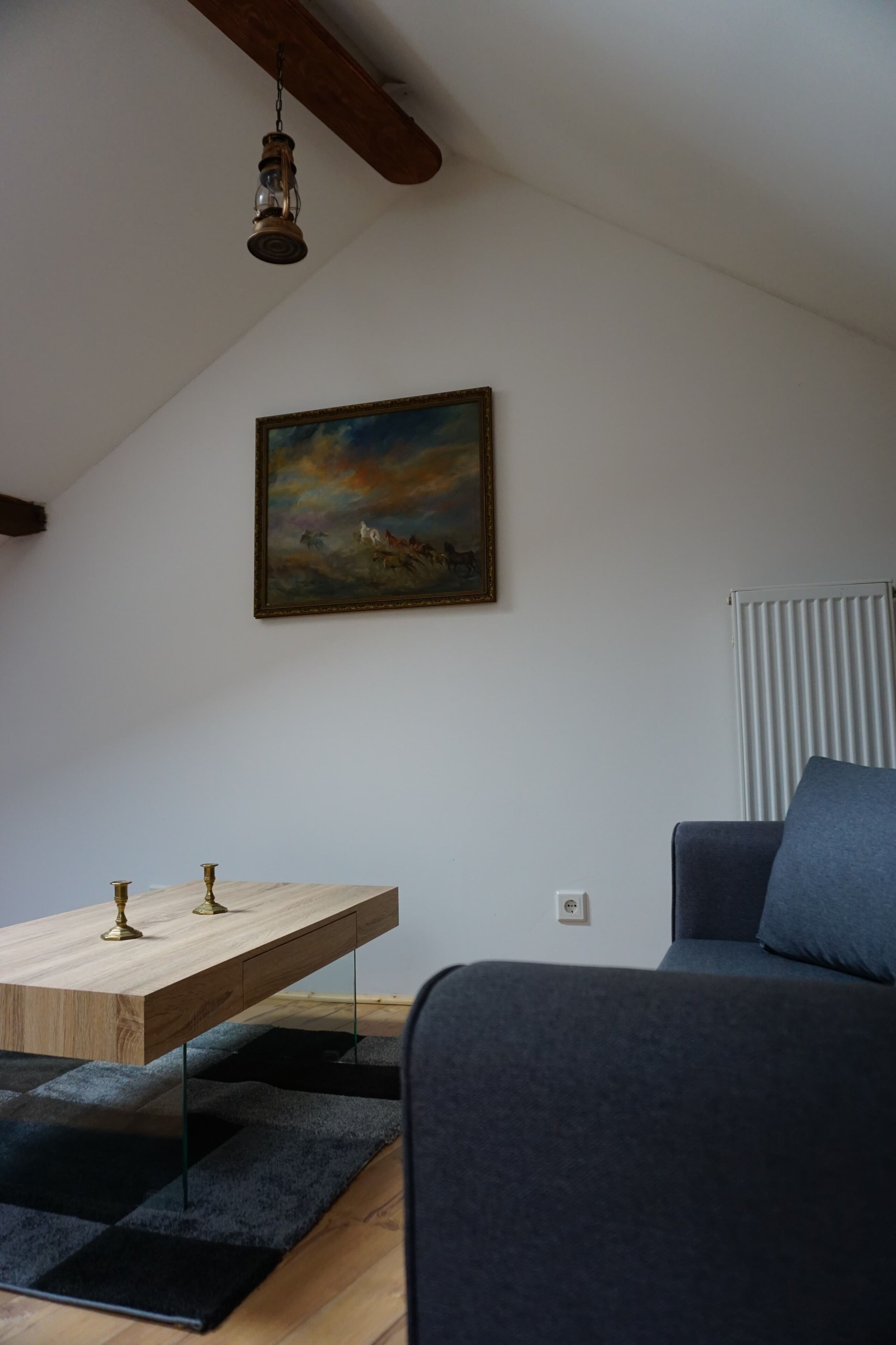 Una habitación con una mesa de comedor de madera, un sofá oscuro, un cuadro en la pared y un ventilador de techo.