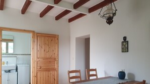 Ein Holztisch mit Stühlen, eine Holztür und eine Küchenzeile mit Spüle und Geräten.