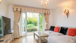 A living room with a sofa, TV, wooden coffee table, and curtains.