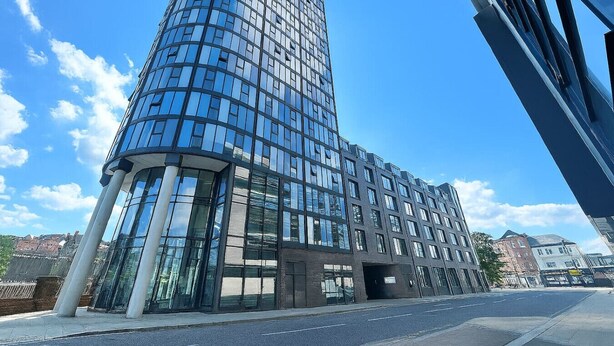 A modern high-rise building with a curved glass facade, large windows, and a prominent entrance.