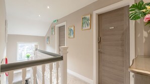 A hallway with a staircase, wooden doors, and framed artwork on the walls. - Moat House Penthouse Suite - 2 Bed  2 Bath (Rawtenstall)
