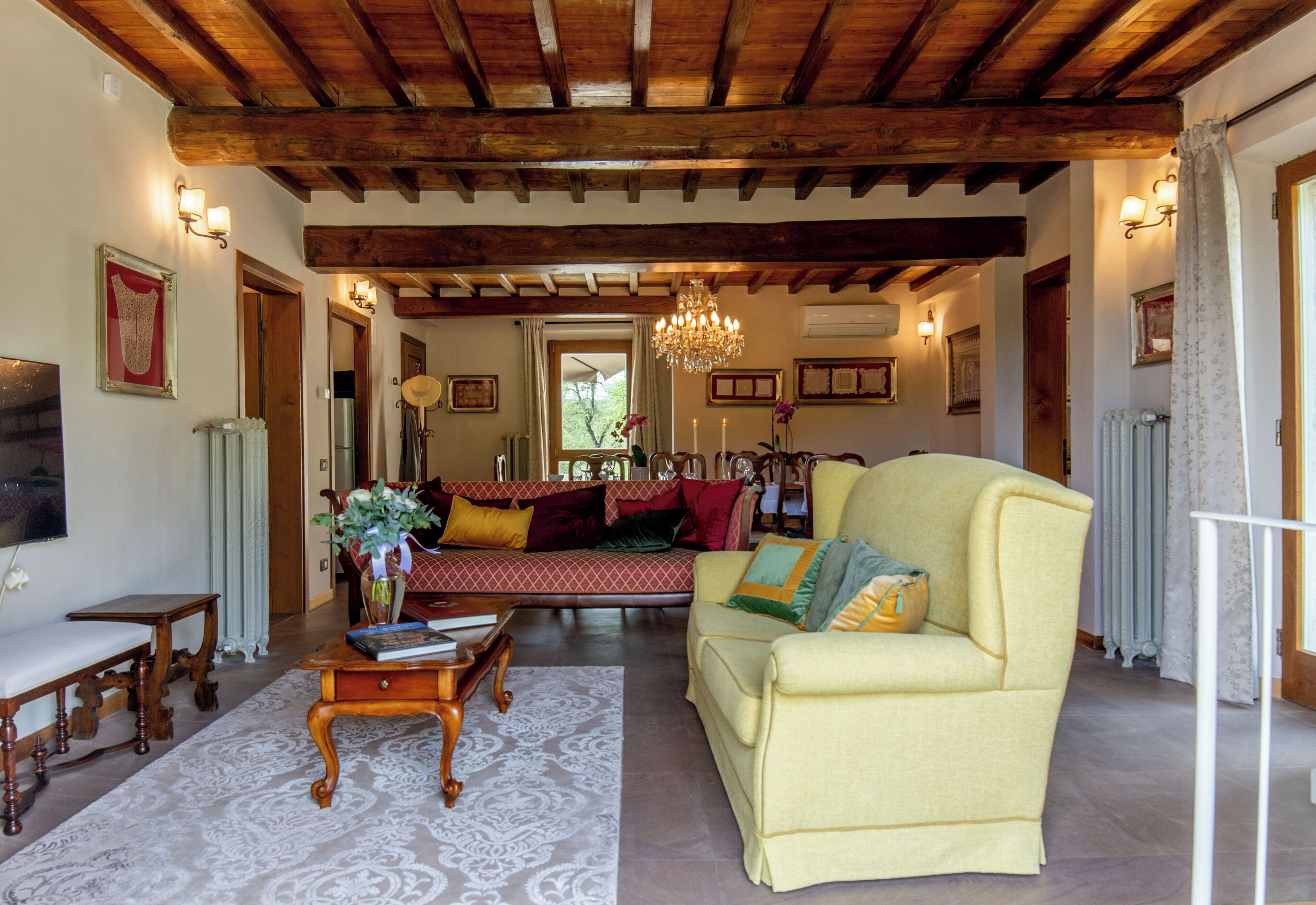 A living room with a yellow sofa, a wooden coffee table, and a chandelier.