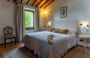 Een slaapkamer met een bed, een stoel, een tafel en een raam met gordijnen.