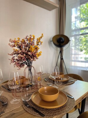 A dining table set with clear glassware, a yellow bowl, and a vase with dried flowers. - Stylish 2-Bed Flat - Heart of London *Zone 2* (London)
