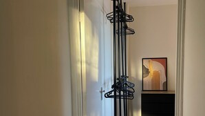 A hallway with a coat rack, a framed abstract painting, and a wooden floor.