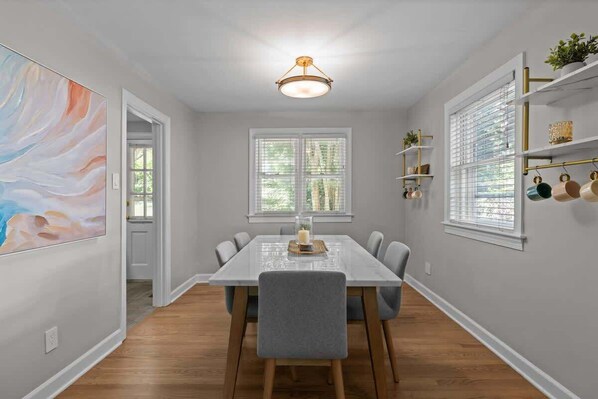 A dining area with a white table, grey chairs, and a ceiling light fixture. - Urban Escape | Near Downtown (Raleigh)