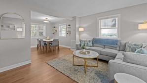 A modern living room with a gray sofa, a round coffee table, and a dining area with a table and chairs. - Urban Escape | Near Downtown (Raleigh)