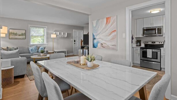 A modern living room with a marble dining table, grey sofas, and a kitchen with white cabinets and stainless steel appliances. - Urban Escape | Near Downtown (Raleigh)