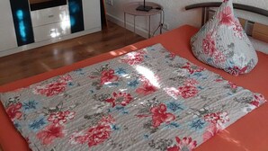 A bedroom with a bed, a bedside table with a lamp, and a mirror reflecting the room.