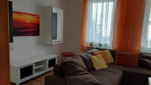 A living room with a sofa, a TV, and a painting.