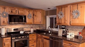 Une cuisine moderne avec des meubles en bois, des appareils électroménagers en acier inoxydable et un dosseret carrelé.