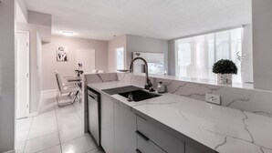 Una cocina moderna con encimera de mármol, un lavamanos y un comedor con una silla y una mesa.