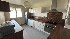 Eine Küche mit Kühlschrank, Herd, Spüle und Schränken.