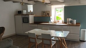 Una cocina compacta con una mesa, sillas, microondas y cafetera.