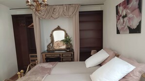 Une chambre à coucher avec un lit, une commode, un miroir et un tableau.