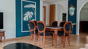 Un coin repas avec une table et des chaises en bois, un téléviseur et un élément décoratif mural.