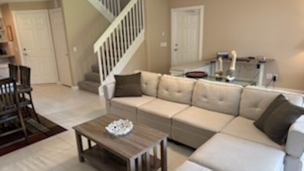 Un salon avec un canapé d’angle beige, une table basse en bois et un escalier.