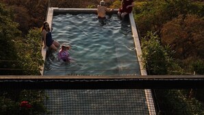 Et roolftop infinity pool med udsigt over et skovlandskab.