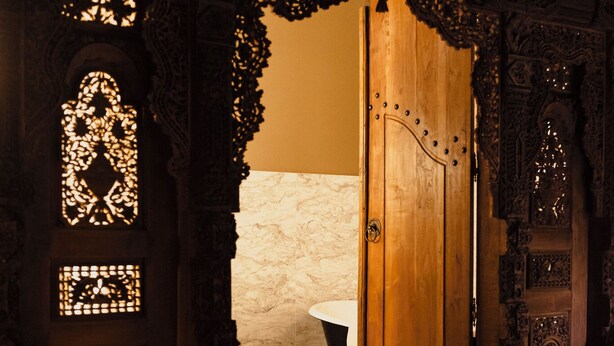 Una puerta de madera ornamentada con tallas intrincadas y un pequeño ventanal con un diseño decorativo.