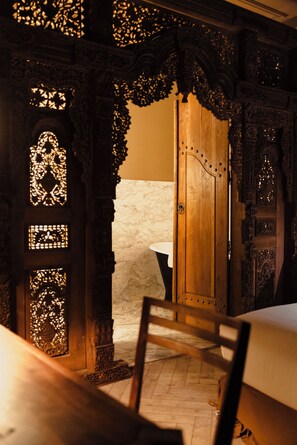 An ornate wooden door with intricate carvings and a small window with a patterned design. - Maison Maubreuil (Nantes)