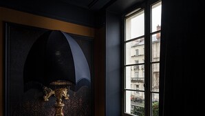 Una habitación con una puerta oscura, una ventana que ofrece vistas a edificios y una lámpara decorativa.