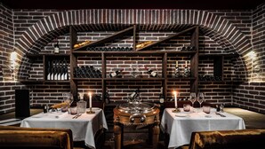 Un restaurante de paredes de ladrillo con mesas dispuestas para comer, botellas de vino en estantes y una urna decorativa central.