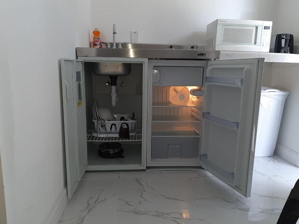 Une cuisine compacte équipée d’un réfrigérateur intégré, d’un four à micro-ondes et d’une machine à café.