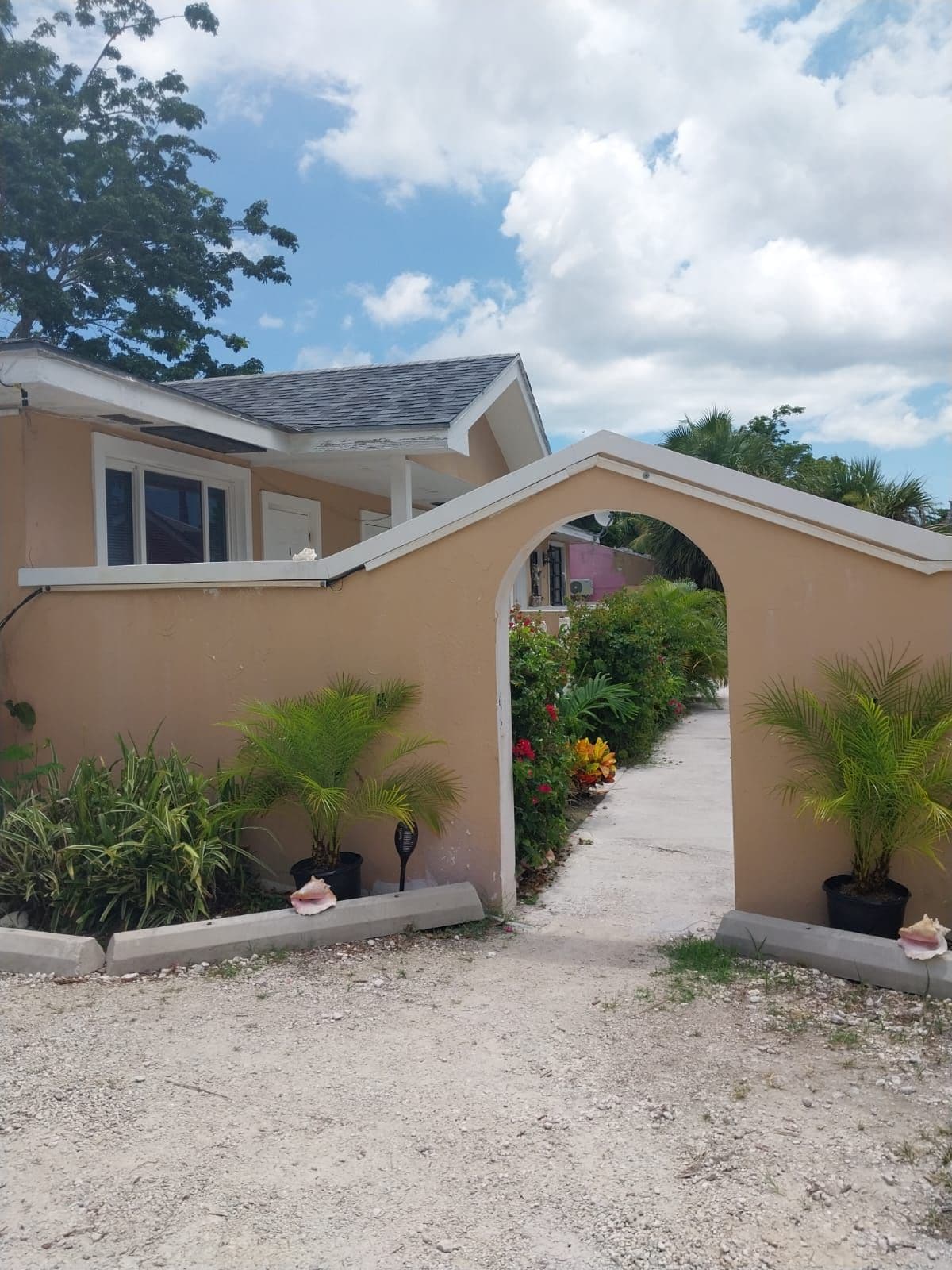 A house with a covered entrance, potted plants, and a gravel driveway.